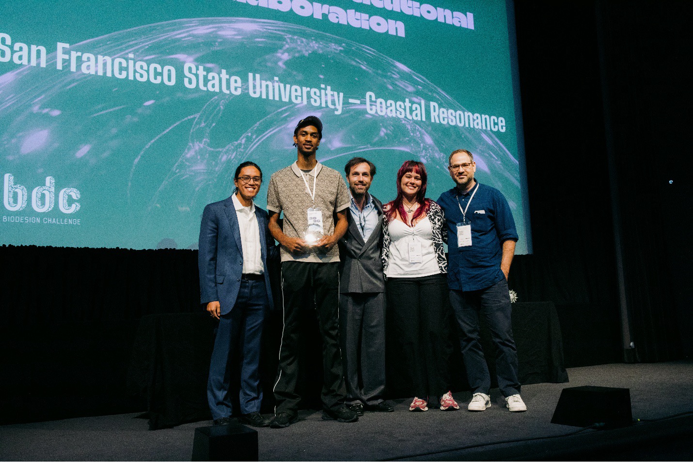 School of Design students Dominic Taylor and April Anderson (and Jason Lee, in absentia) receive the 2026 Biodesign Challenge Award for Outstanding Institutional Collaboration from Biodesign Executive Director Paul Rubery (center), Program Manager Michael Balangue (left) and Founder, former Executive Director, Board Member and Jury Member Daniel Grushkin (right). The award ceremony took place at NYC MoMA. (Photo by Shannon Carroll). 