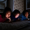 Three girls staring at their smartphones in the dark while ignoring each other