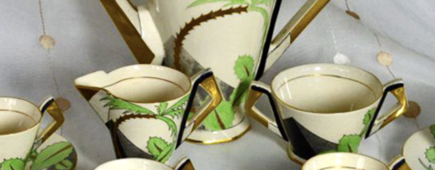 A coffee set with a coffee pot and four coffee cups with saucers. All objects have an ivory, cream white color as a base and some decoration in the form of swoshes in green and gold color. 