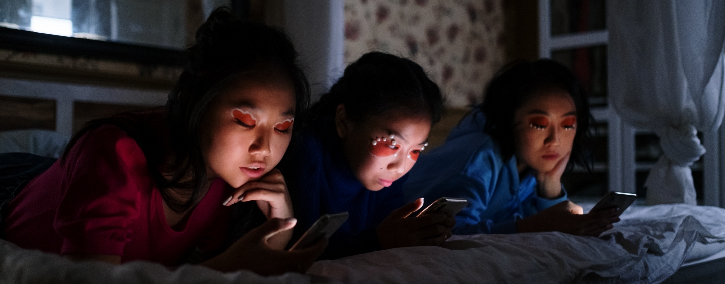 Three girls staring at their smartphones in the dark while ignoring each other