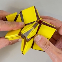 Hands folding an origami-like material, the prototype of Prof. Trogu