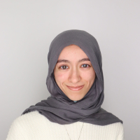 Tasnim Saada, MA Design Graduate Student, in grey hajib and white sweater